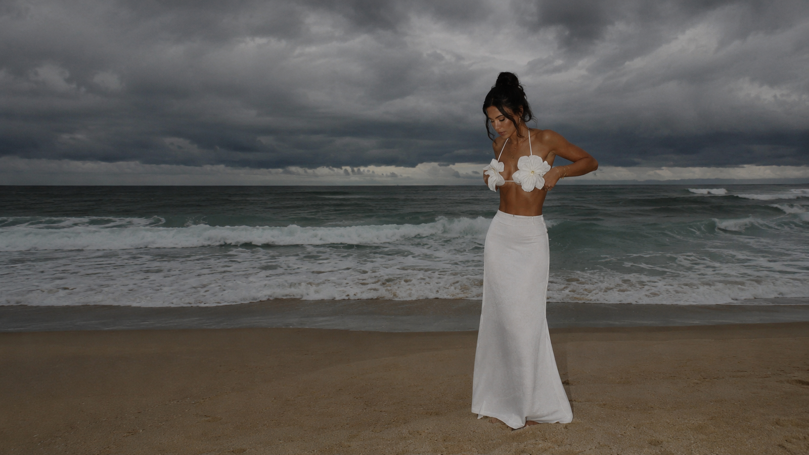 Woman wearing a white floral beach two-piece set with a long skirt on the beach